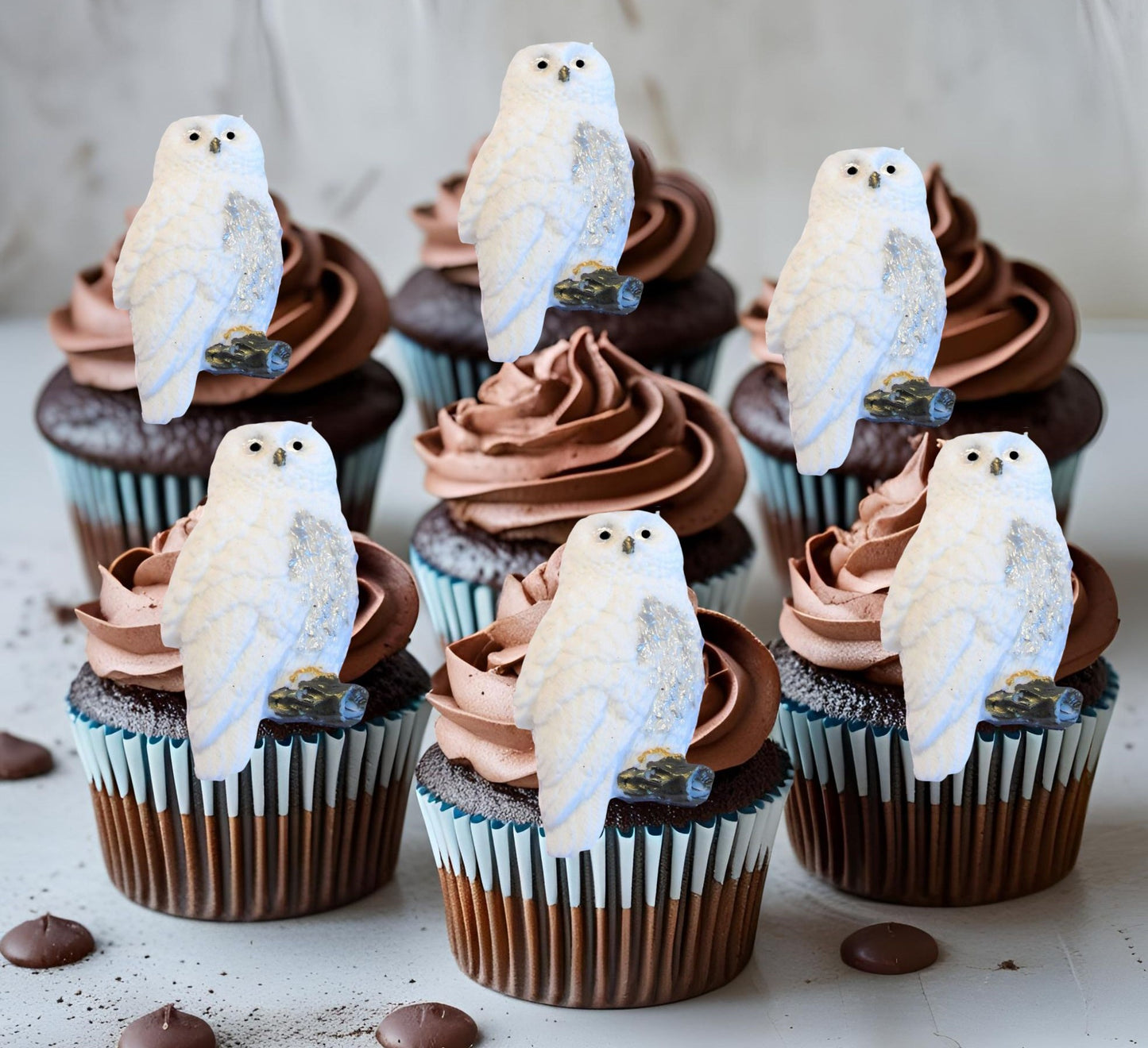 Cupcakes with chocolate frosting topped with owl decorations on a light background.