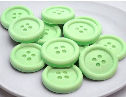 Green edible buttons on a white plate with a white cloth background