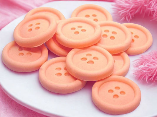 Peach-colored shaped buttons on a white plate with a pink background