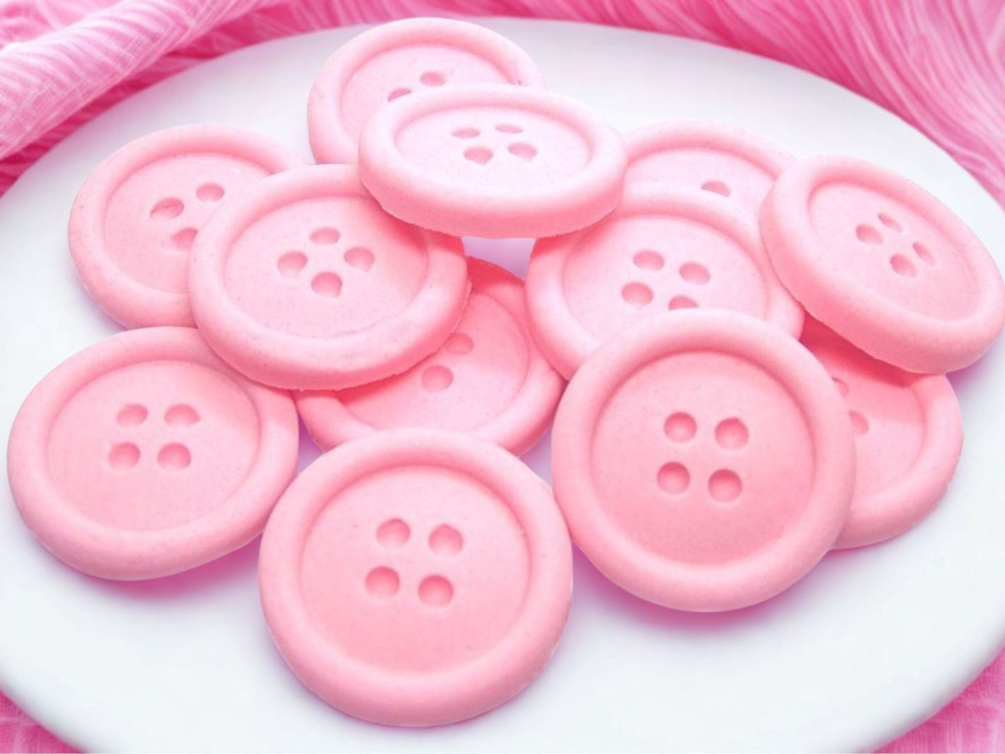 Pink-colored shaped buttons on a white plate with a pink background