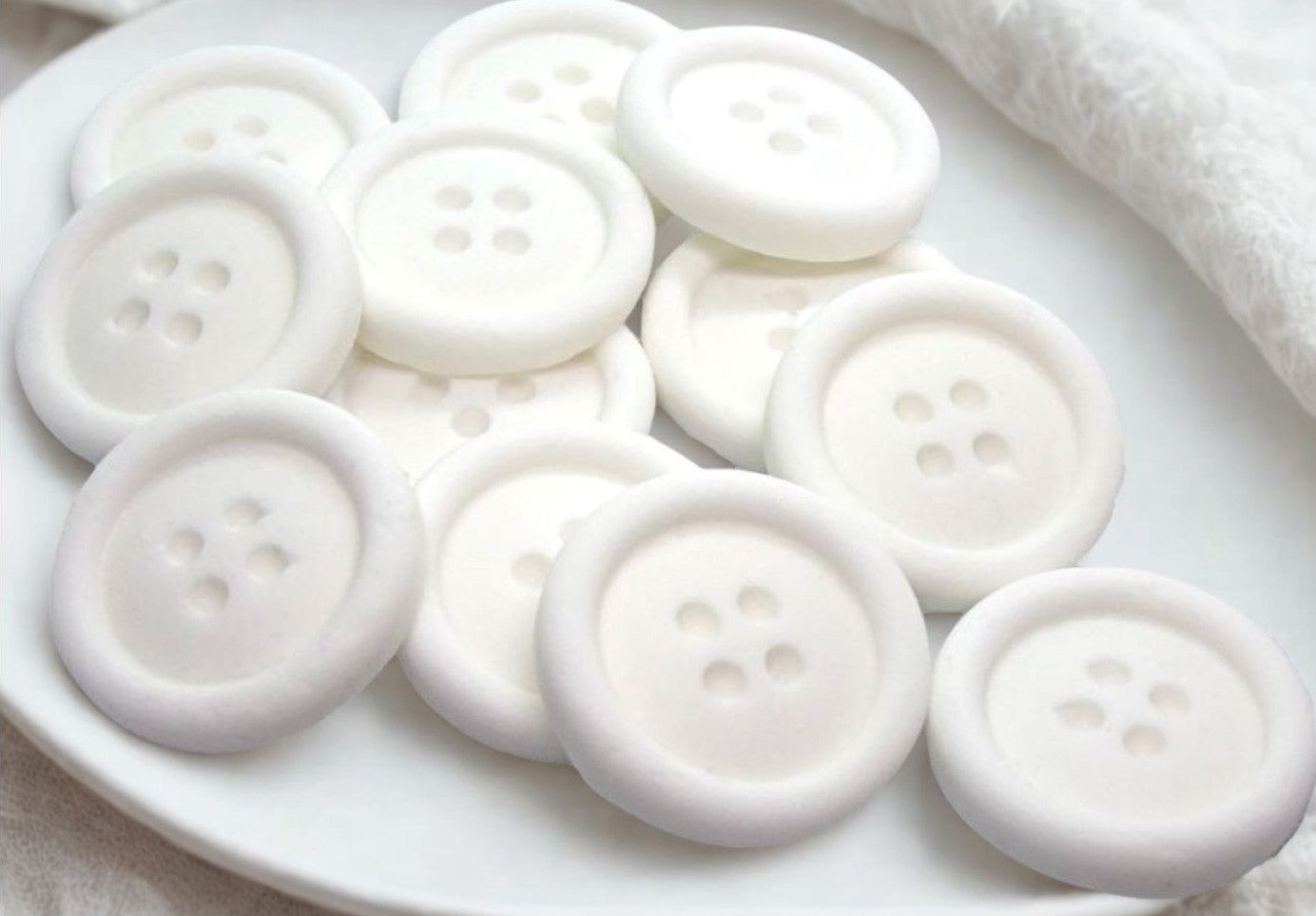 White edible buttons on a white plate with a white cloth background