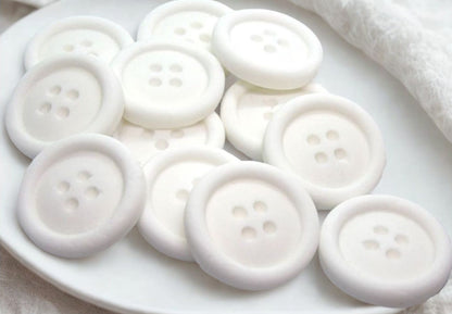 White edible buttons on a white plate with a white cloth background