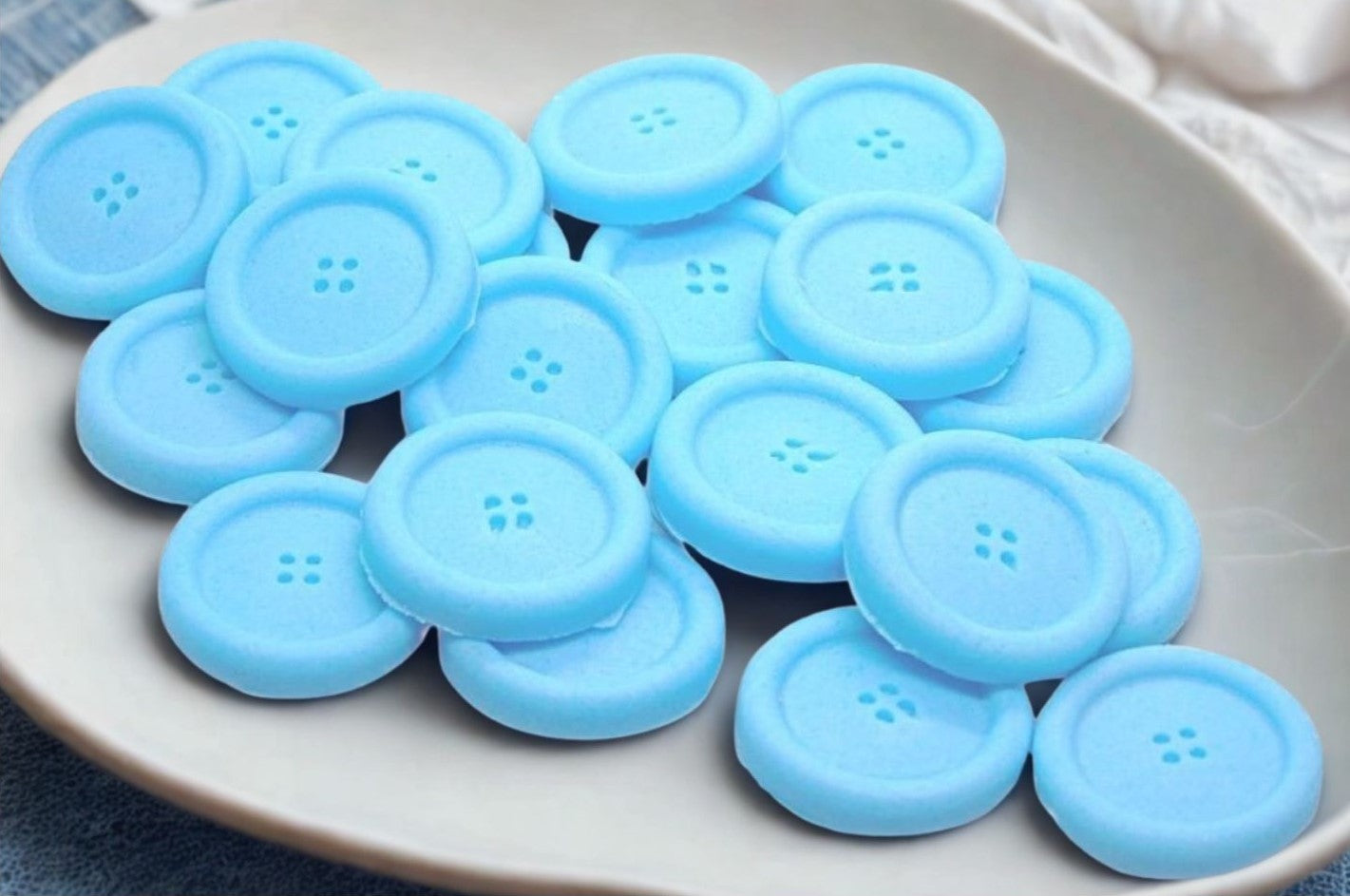 Bl coloured edible buttons for baked goods decorations shown in a white dish with a blue cloth in the background