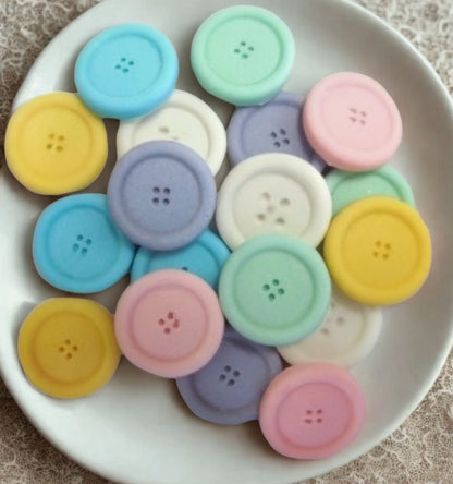 mixed coloured edible buttons for baked goods decorations shown in a white dish with a white cloth in the background