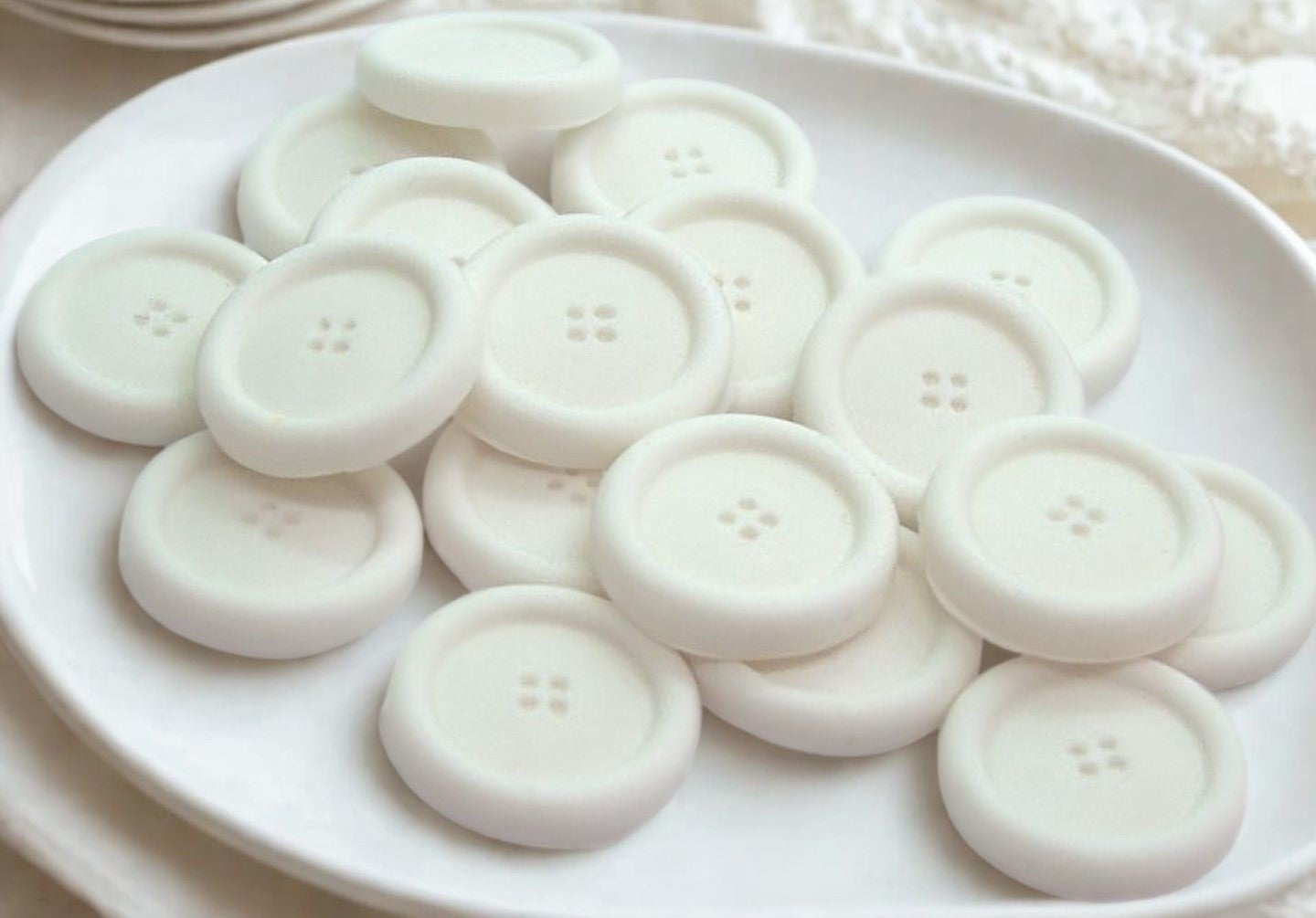White edible buttons for baked goods decorations shown in a white dish with a white cloth in the background