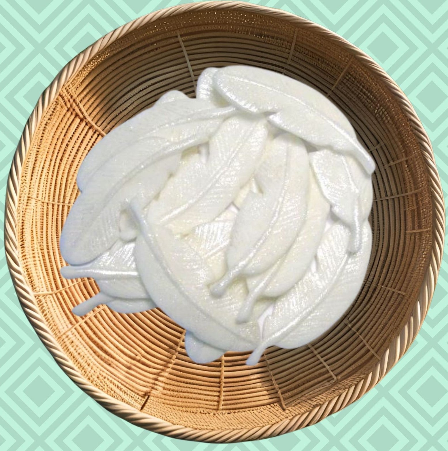 White glittered feathers  edible decorations on a woven basket against a teal background