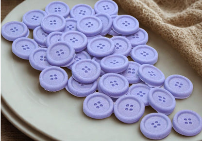 purple edible buttons on a white plate with a fawn cloth in the background