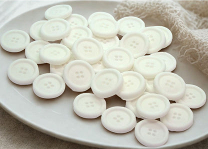 White edible buttons on a white plate with a white cloth in the background