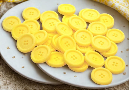 Yellow edible buttons on a white plate with a yellow cloth in the background