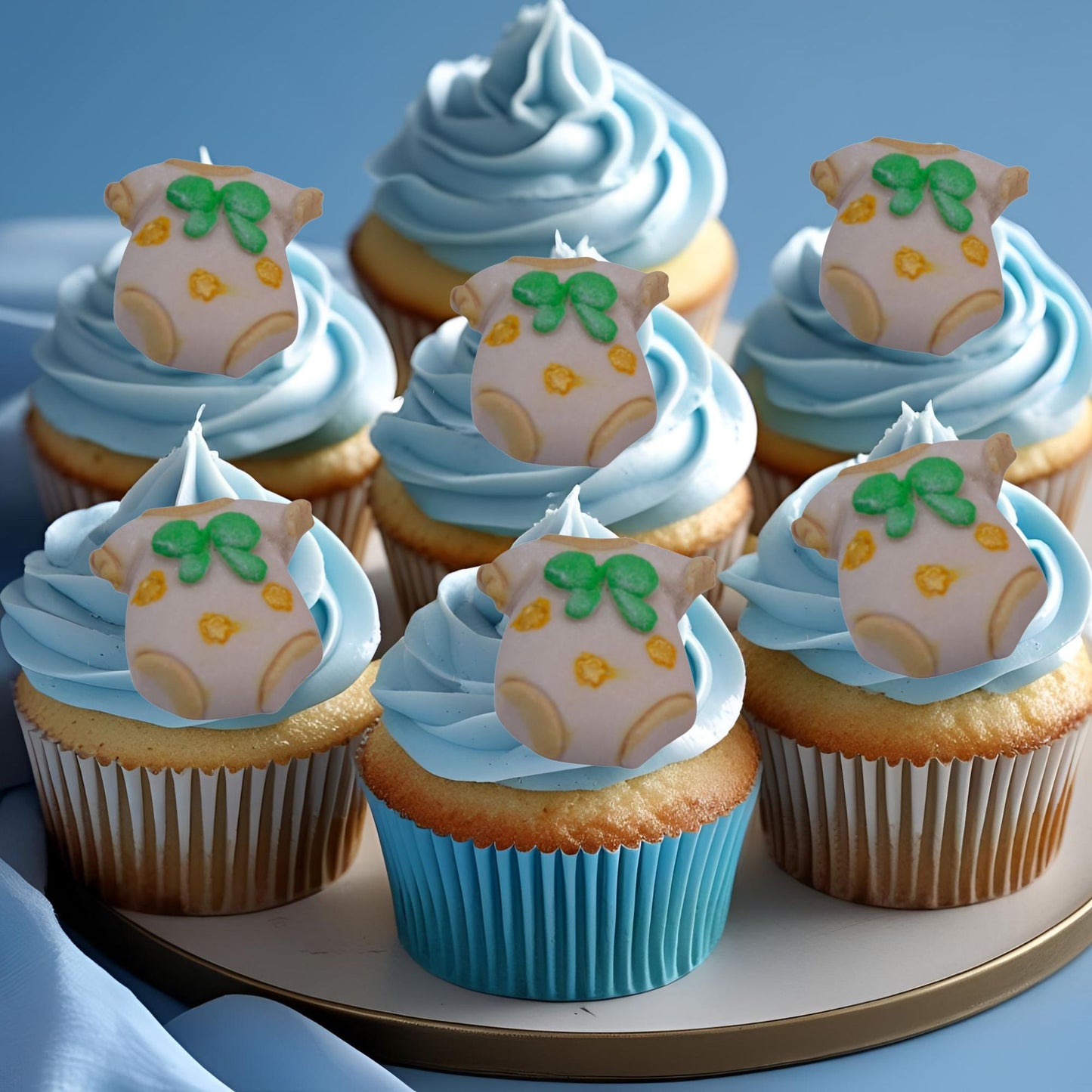 Cupcakes with blue frosting and baby onesie edible decorations on a plate.