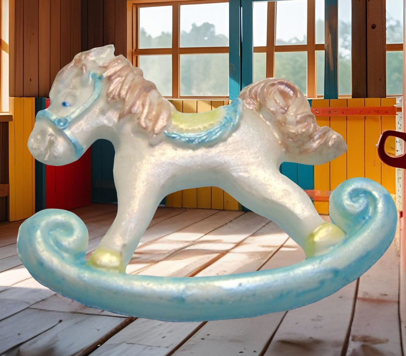 White and blue rocking horse cake topper decorations shown with an image in a playroom with wooden floor and colorful walls.