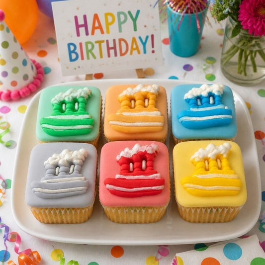Colorful birthday cupcakes with ocean-themed decorations on a plate, accompanied by a 'Happy Birthday!' card.