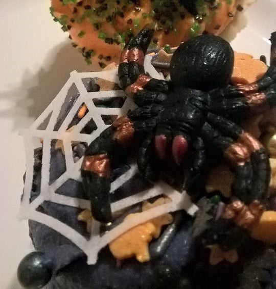 Black edible spider  on a decorative cupcake with a spider web