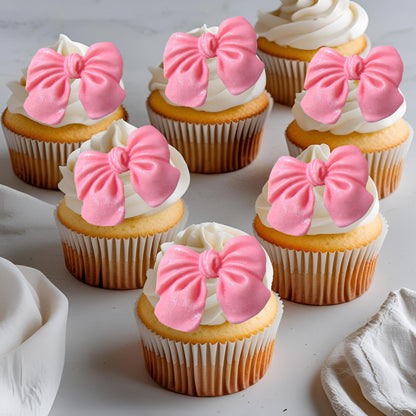 Cupcakes with pink glittered edible  bow decorations on a light background
