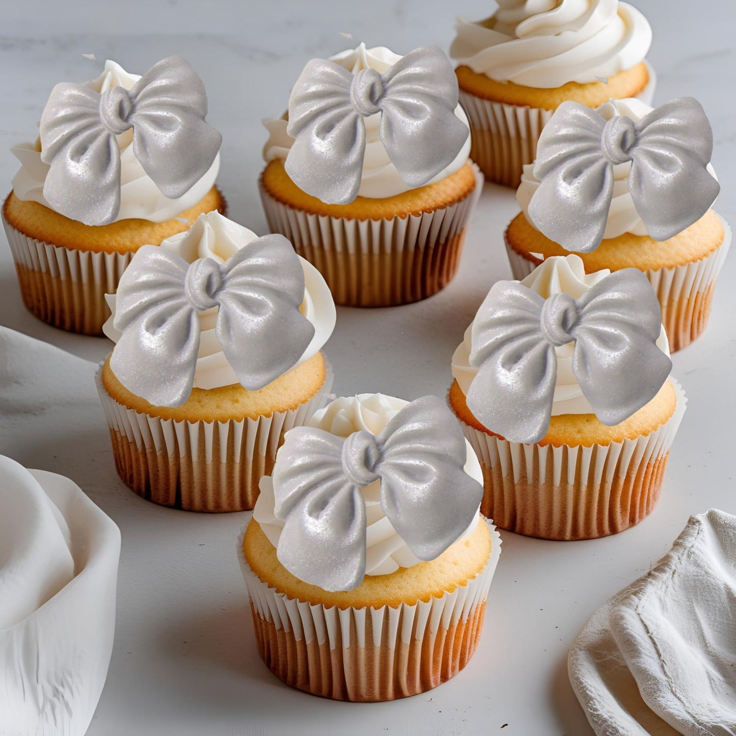Cupcakes with Silver glittered edible  bow decorations on a light background