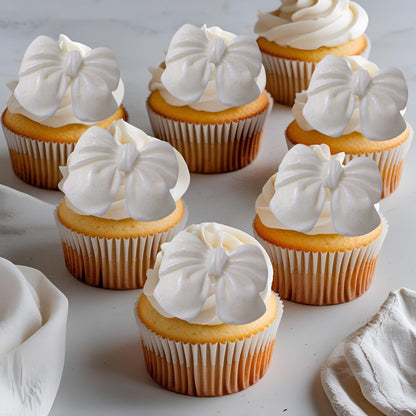 Cupcakes with white glittered edible  bow decorations on a light background