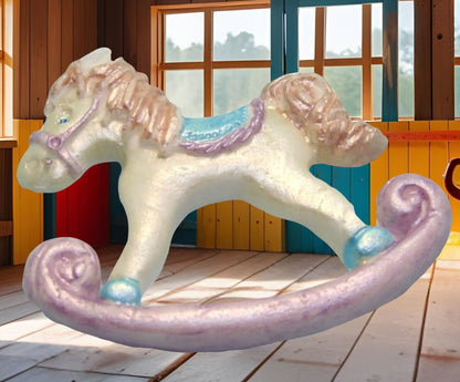 White and pink rocking horse cake topper decorations shown with an background image in a playroom with wooden floor and colorful walls.