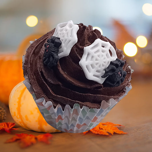 Chocolate cupcake with spiderweb edible decorations on a blurred Halloween-themed background