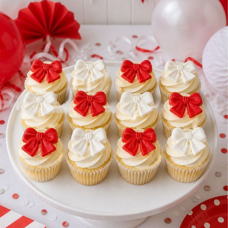 Decorative cupcakes with red and white bows on a white plate, festive background.