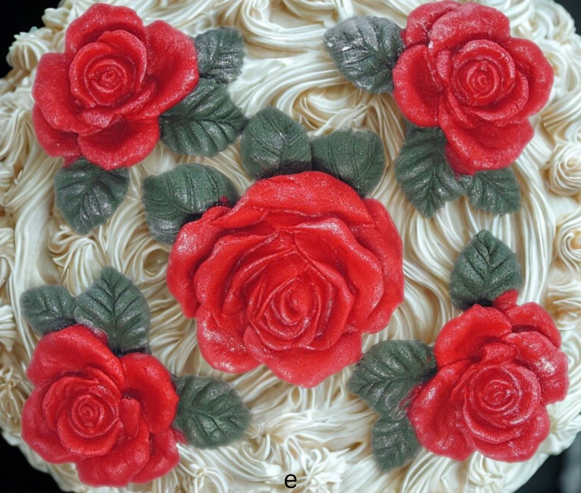 Close-up of a cake with red rose decorations on white frosting