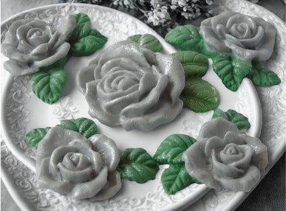A set of edible glittered Silver  rose garland cake toppers with a large centre rose, on a plate