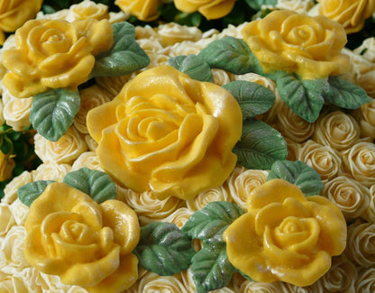 Close-up of a cake with Yellow rose and green leaf decorations on white frosting